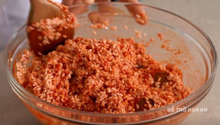 Trộn đều gạo nếp đã ngâm và phần thịt gấc, cho 1 muỗng cà phê muối